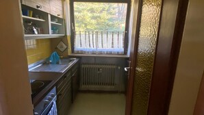 Une cuisine étroite avec une fenêtre, un radiateur et des placards en bois.