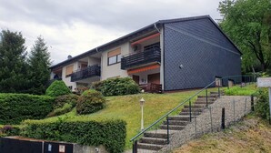 Un bâtiment moderne à deux étages, doté de balcons, d’un escalier et d’un jardin bien entretenu.