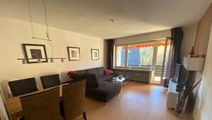 Un salon moderne avec un canapé, des fauteuils, une table basse et un téléviseur.