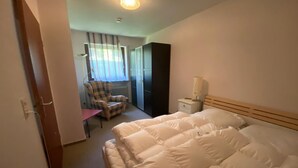 Une chambre d’hôtel avec un grand lit, une chaise, un bureau et un radiateur.