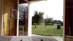 Un dormitorio con cama, ventana y vistas a un jardín césped con árboles y una valla.