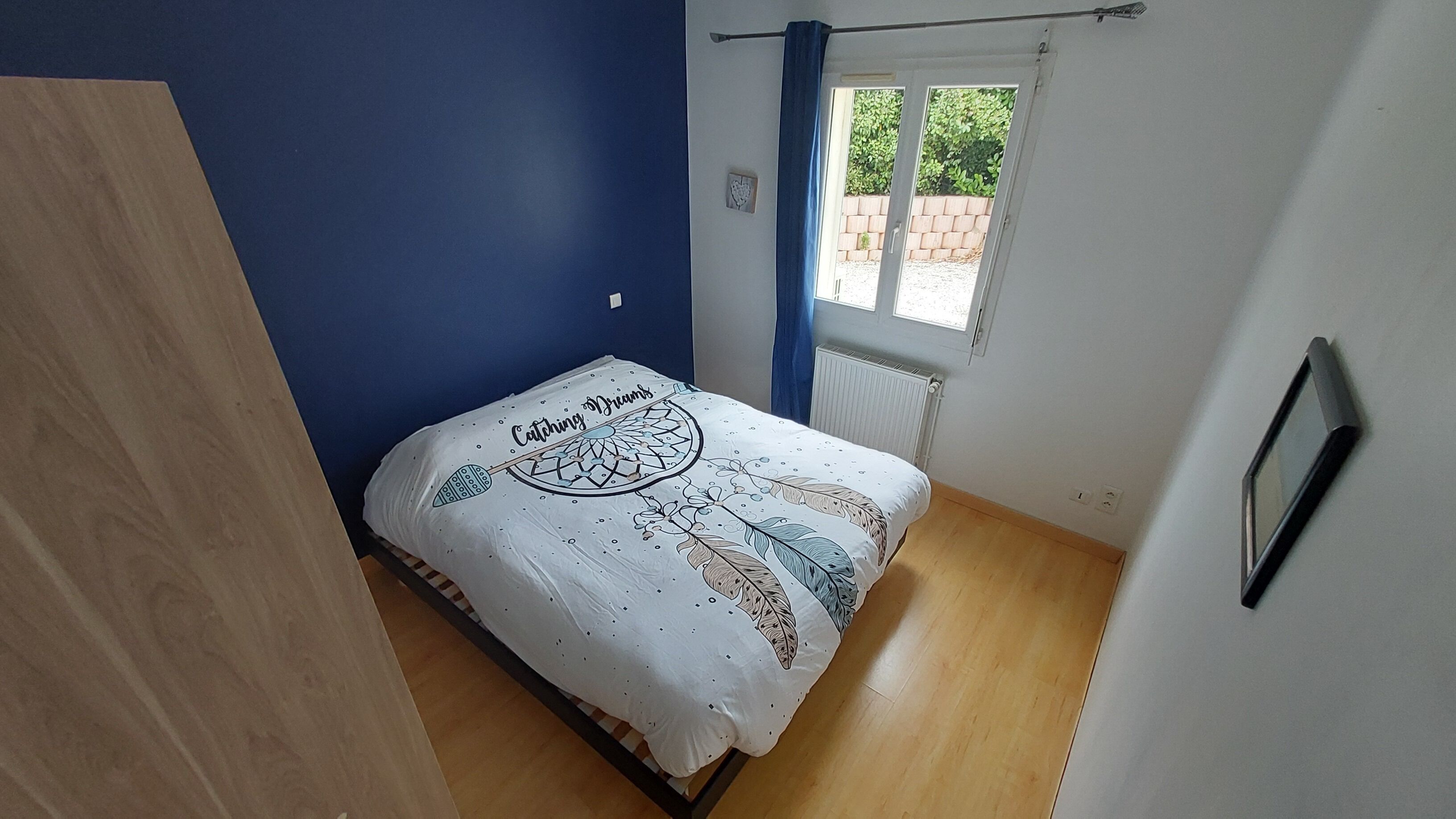 A bedroom with a bed, a window, and a radiator.