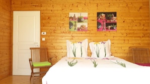 Una habitación con paneles de madera, una cama, una silla y dos adornos en la pared.