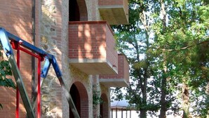 Un bâtiment en briques avec une balançoire et une structure de jeux verte.