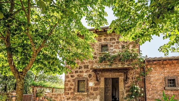 A rustic stone building with a wooden door and windows, surrounded by lush greenery and potted plants. - Stunning private villa with WIFI, private pool, TV, patio, pets allowed and panoramic view (Vetralla)