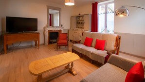 Ein Wohnzimmer mit Fernseher, Kamin, Sofa, Tisch und Schrank.