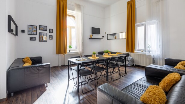 Un salon moderne avec un coin repas, comprenant un canapé, une table à manger avec des chaises et un téléviseur à écran plat fixé au mur.