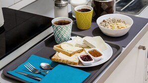 Een ontbijtplateau met toast, jam en een kop koffie op een aanrecht.
