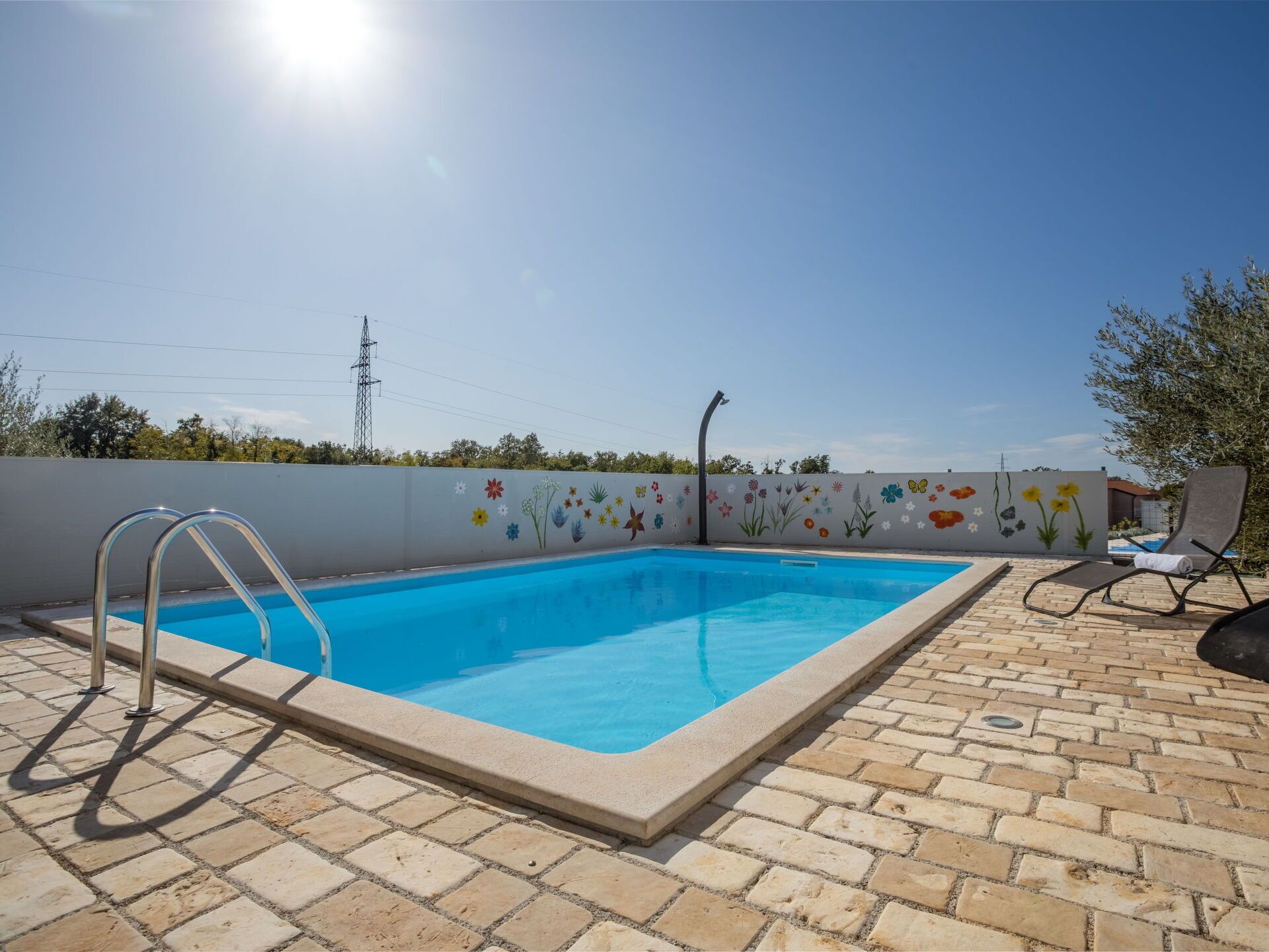 Una piscina rectangular d'aigua cristal·lina i blava, envoltada per un pati enrajolat.