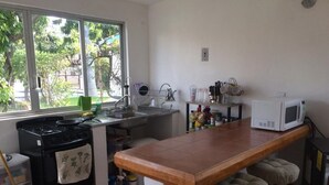Cocina compacta con estufa, fregadero y microondas. Una ventana ofrece vistas a zonas verdes.