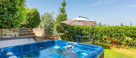 Un bain à remous avec un mur en pierre et de la verdure en arrière-plan.