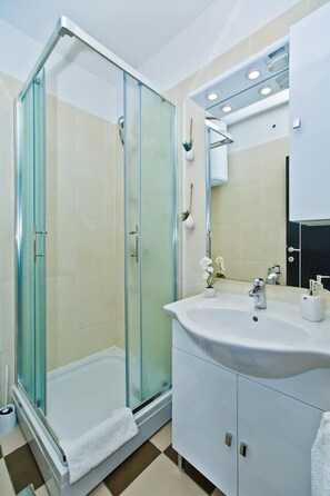 A modern bathroom with a glass-enclosed shower, a white sink, and a large mirror above the vanity. - Apartments Nina Hvar town (Hvar)