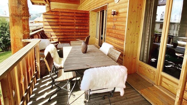 Una cabaña de madera con comedor, que incluye una mesa, sillas, una lámpara colgante de mimbre y un ventanal amplio.