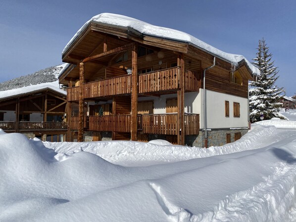 A wooden chalet with a balcony, surrounded by snow. - 6-person 4* apartment top of the resort, 100 m slopes. Bright, quiet residence (Huez)