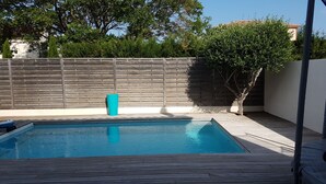 A rectangular swimming pool with a wooden deck surrounding it. - Villa with pool, close to beaches and town center. (Narbonne)