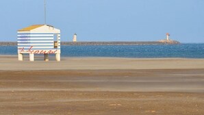 A beachside building with a striped facade and a red sign. - Villa with pool, close to beaches and town center. (Narbonne)