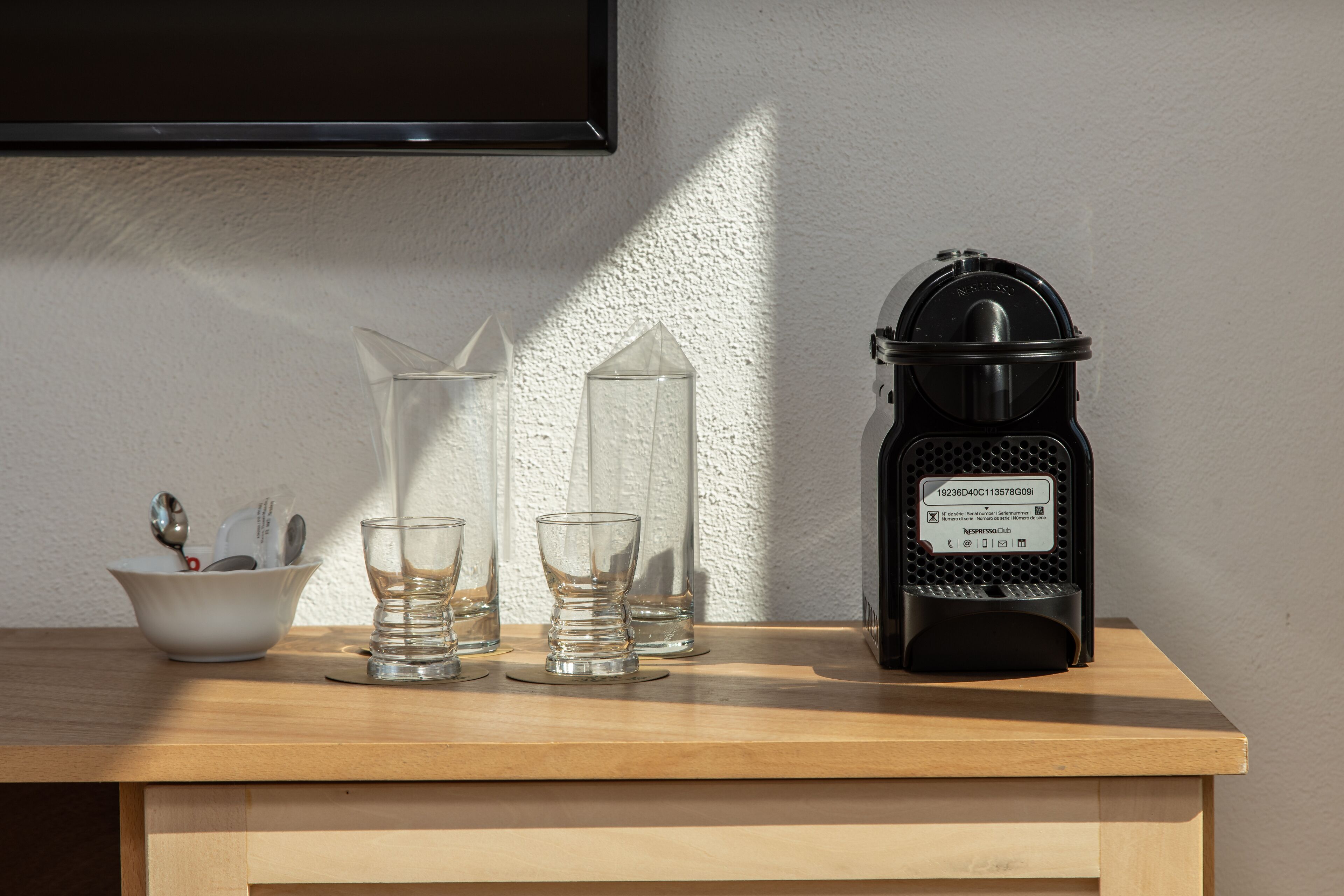 A wooden table with a black lantern, three clear glasses, and a white bowl with utensils.