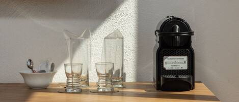 A wooden table with a black lantern, three clear glasses, and a white bowl with utensils.