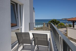 A balcony with two chairs, a view of the sea, and a building with a white facade. - JI Hotel (Sozopol)