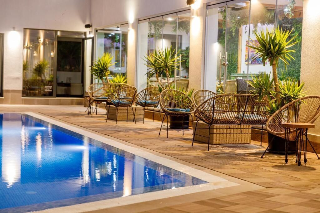 An indoor swimming pool area with wicker chairs and potted plants.