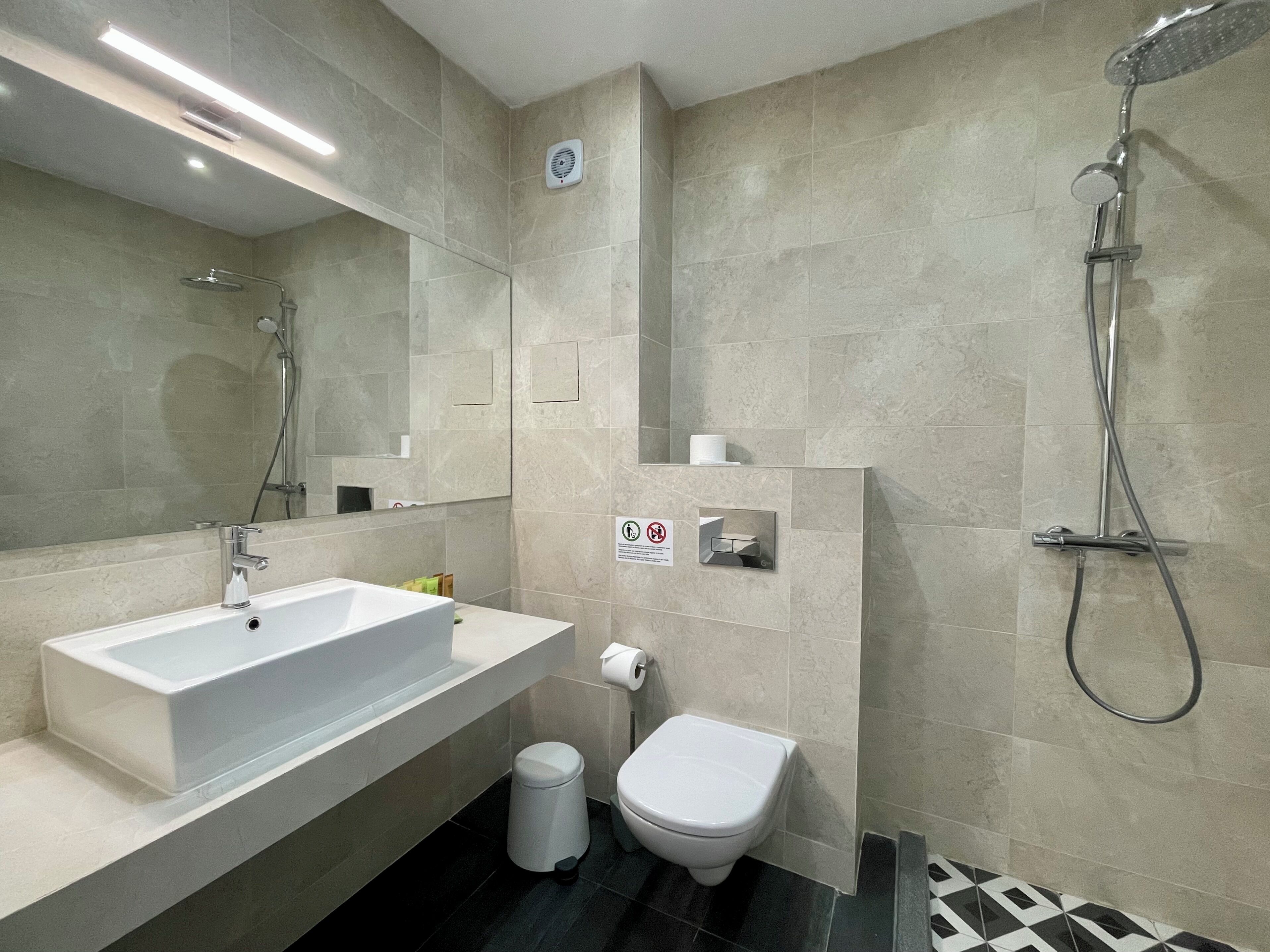 A modern bathroom with a large sink, toilet, and shower.