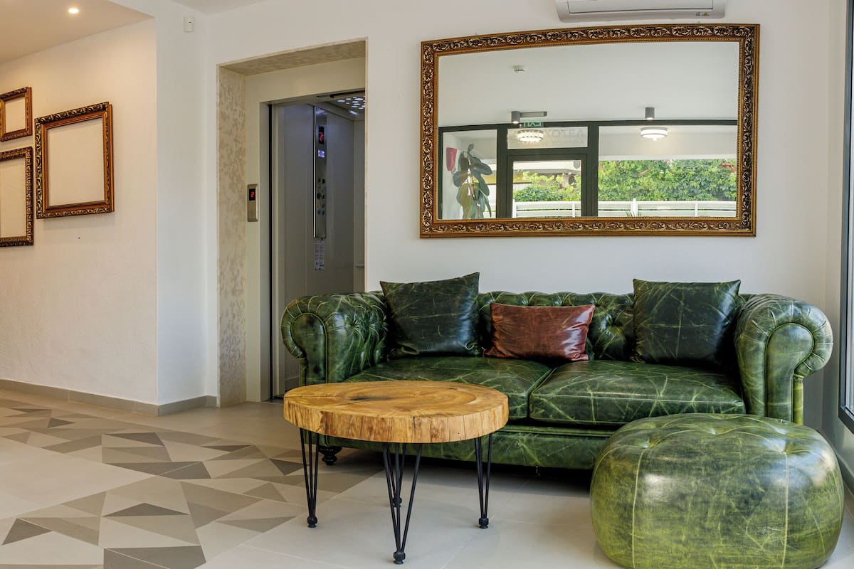 Un vestíbulo con un sofá de cuero verde, una mesa de centro de madera, un reloj y cuadros en la pared.