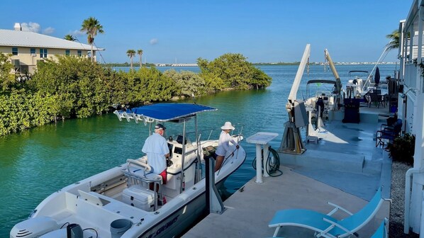 A boat docked at a marina with a covered seating area and lounge chairs. - **TIDEWATER VIEWS** Cottage + Boat Slip + Pool + Last Key White Glove Service... (Cudjoe Key)