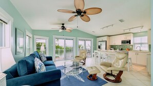 A spacious living area with a blue sofa, a glass coffee table, and a ceiling fan. - **TIDEWATER VIEWS** Cottage + Boat Slip + Pool + Last Key White Glove Service... (Cudjoe Key)