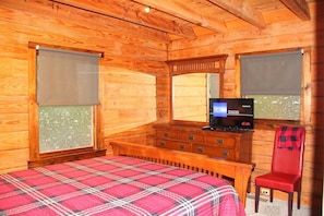 Une pièce en bois avec un lit, une commode, un téléviseur et une chaise.