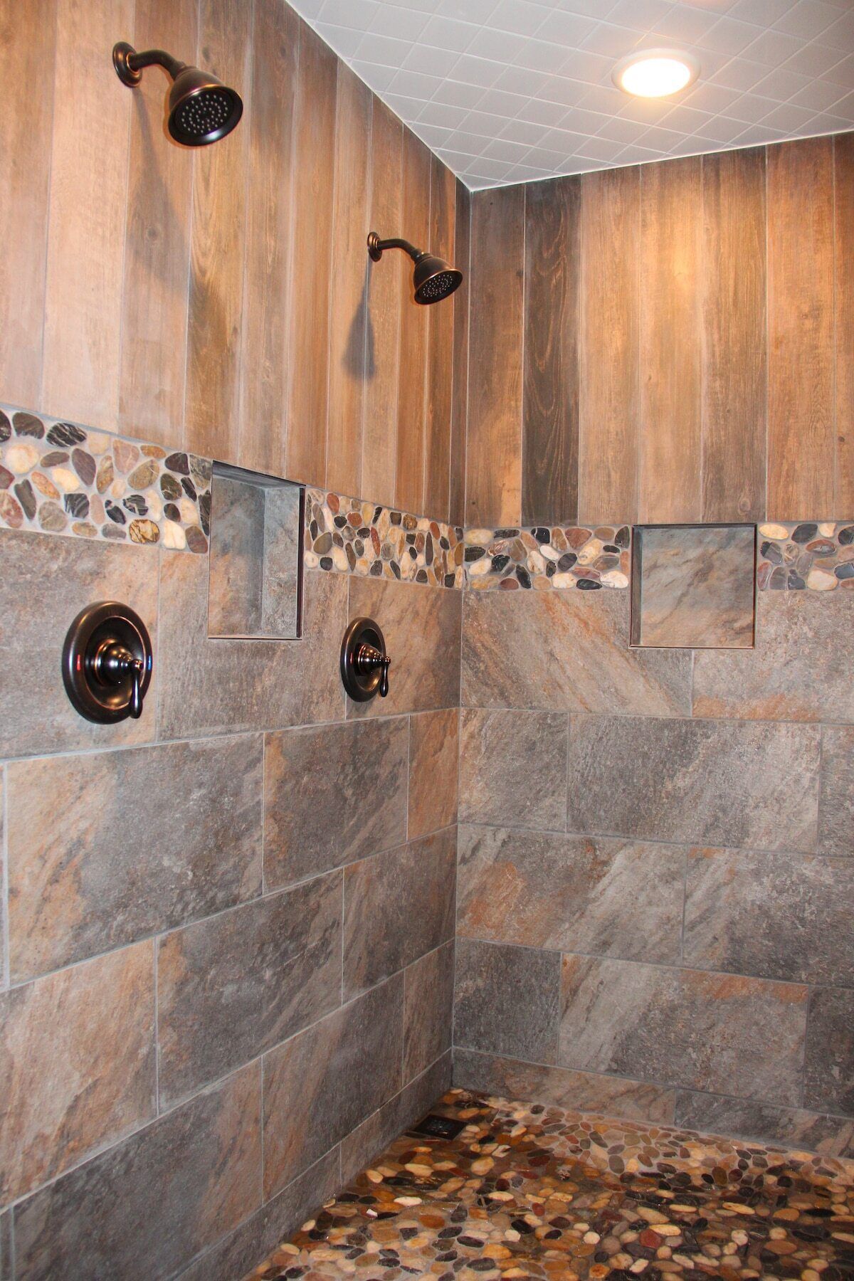 A shower with stone tiles and a pebble mosaic floor.