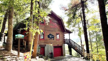 Un rústico granero Red Dog Barn con fachada de madera, un garaje rojo y una escalera que conduce a la entrada.