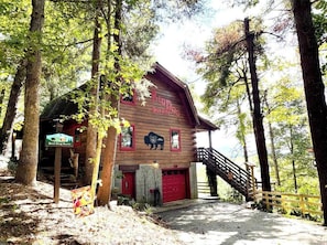 A rustic Red Dog Barn with a wooden exterior, a red garage, and a staircase leading to the entrance.