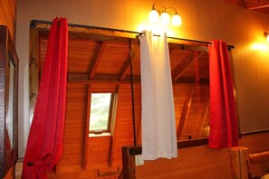 A wooden interior with a window, a shower curtain rod, and a light fixture. - Red Dog Barn: bison walk right in front of cabin! (Clyde)