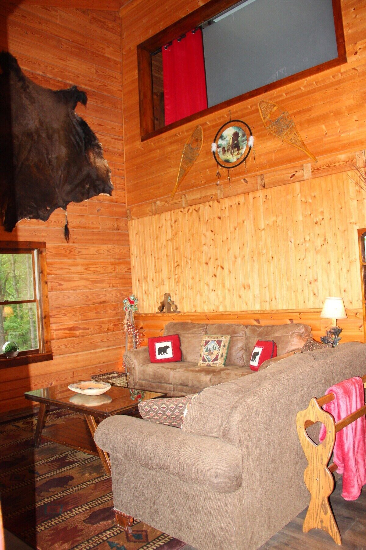 A log cabin interior with a leather sofa, a mounted animal head, and a rustic decor.