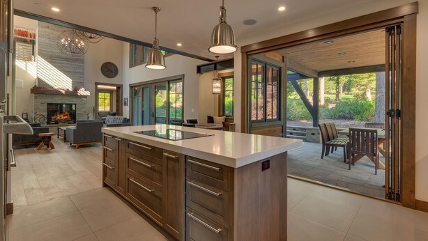 A modern kitchen with a large island, built-in appliances, and a dining area with outdoor seating.