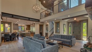 A spacious living room with a grey sofa set, a coffee table, and a dining area with a kitchen in the background.