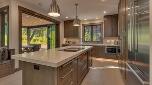 A modern kitchen with a large island, stainless steel appliances, and pendant lighting.