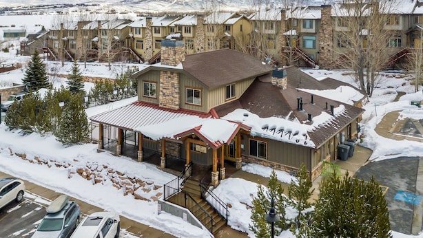 A multi-story residential building with a stone facade, a covered porch, and a snow-covered roof. - Guest-Favorite Ski Home in Bear Hollow w/ Hot Tub – Sleeps 18 – King/Queen Beds (Park City)