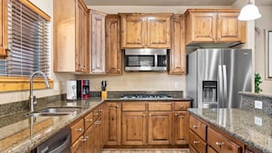 A kitchen with wooden cabinets, granite countertops, stainless steel appliances, and a built-in dishwasher. - Guest-Favorite Ski Home in Bear Hollow w/ Hot Tub – Sleeps 18 – King/Queen Beds (Park City)