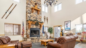 A spacious lobby with a stone fireplace, leather sofas, and skis on the wall. - Guest-Favorite Ski Home in Bear Hollow w/ Hot Tub – Sleeps 18 – King/Queen Beds (Park City)