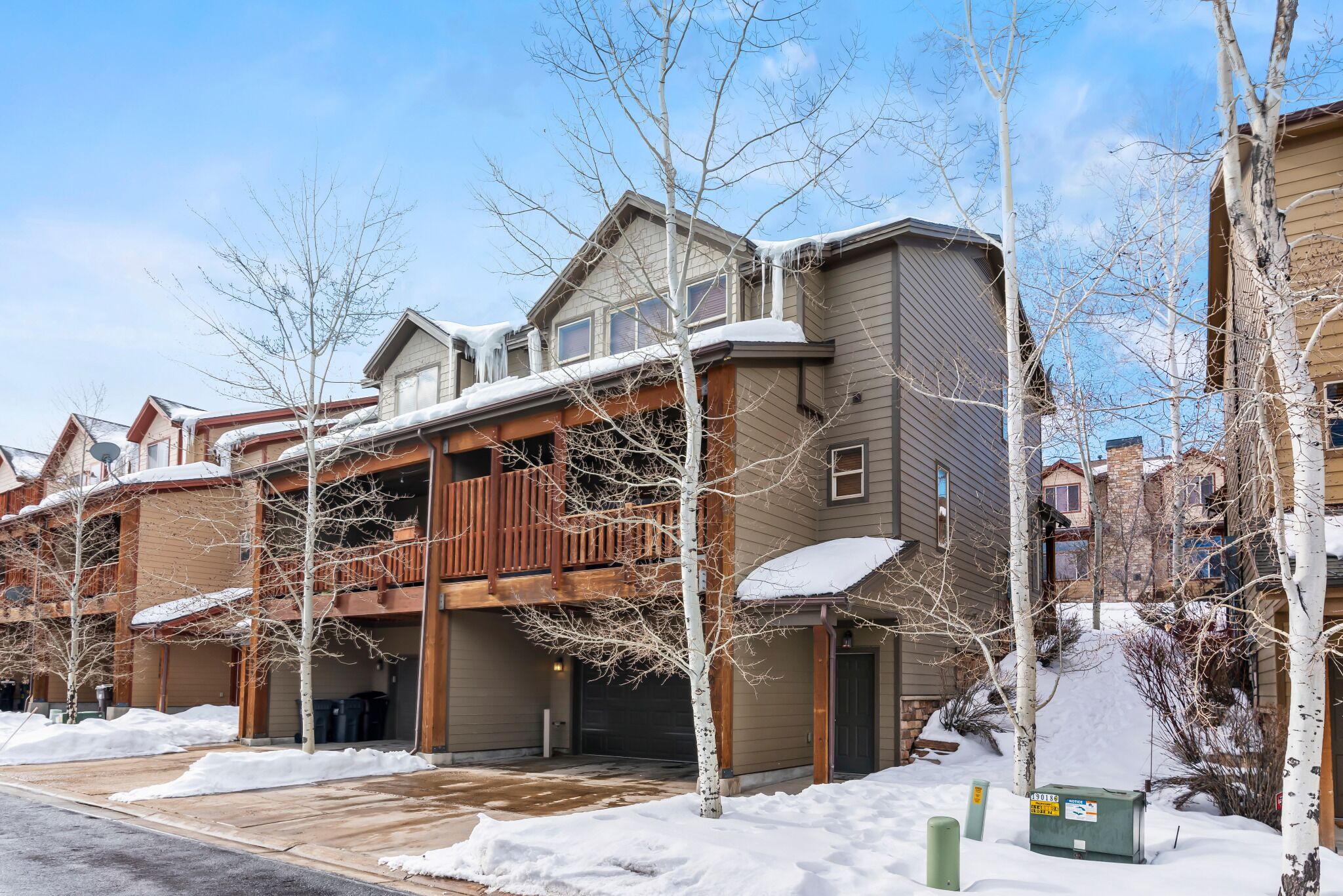 A residential area with houses, some with snow on the roofs, and bare trees.