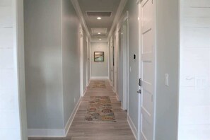A hallway with white walls, a patterned rug, and doors leading to rooms. - Pelican Wharf, Pool/Hot Tub (Crystal Beach)