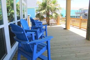 A wooden deck with blue Adirondack chairs and a palm tree. - Pelican Wharf, Pool/Hot Tub (Crystal Beach)