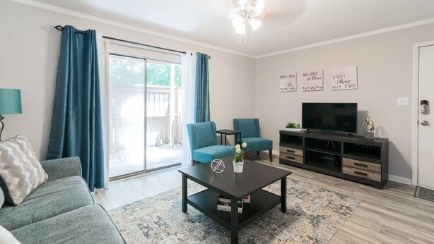 A modern living room with a sofa, two armchairs, a coffee table, and a TV on a wooden stand.