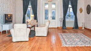 A living room with wooden flooring, a sofa set, a television, and a patterned rug. - Stunning home in Värmlands Nysäter (Värmlands Nysäter)