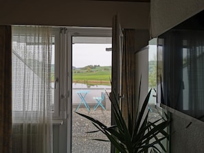 Ein Zimmer mit Blick auf eine grüne Landschaft, einem kleinen Tisch und einer Topfpflanze.