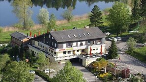 Un chalet doté d’un grand bâtiment, d’un espace de stationnement et d’un lac en arrière-plan.