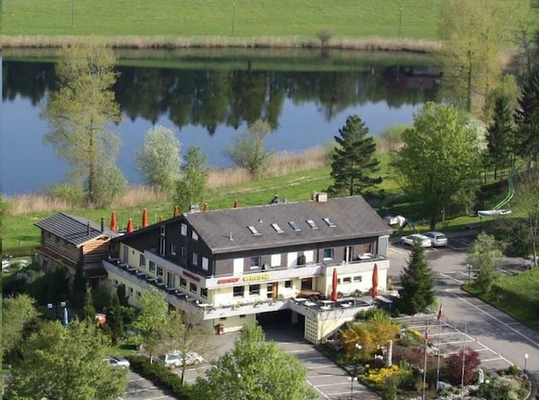 Eine Lodge mit einem großen Gebäude, einem Parkplatz und einem See im Hintergrund.