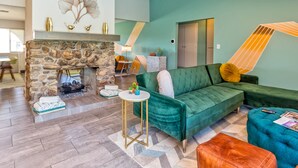 Un salon avec une cheminée en pierre, un canapé vert et une petite table d’appoint ronde.