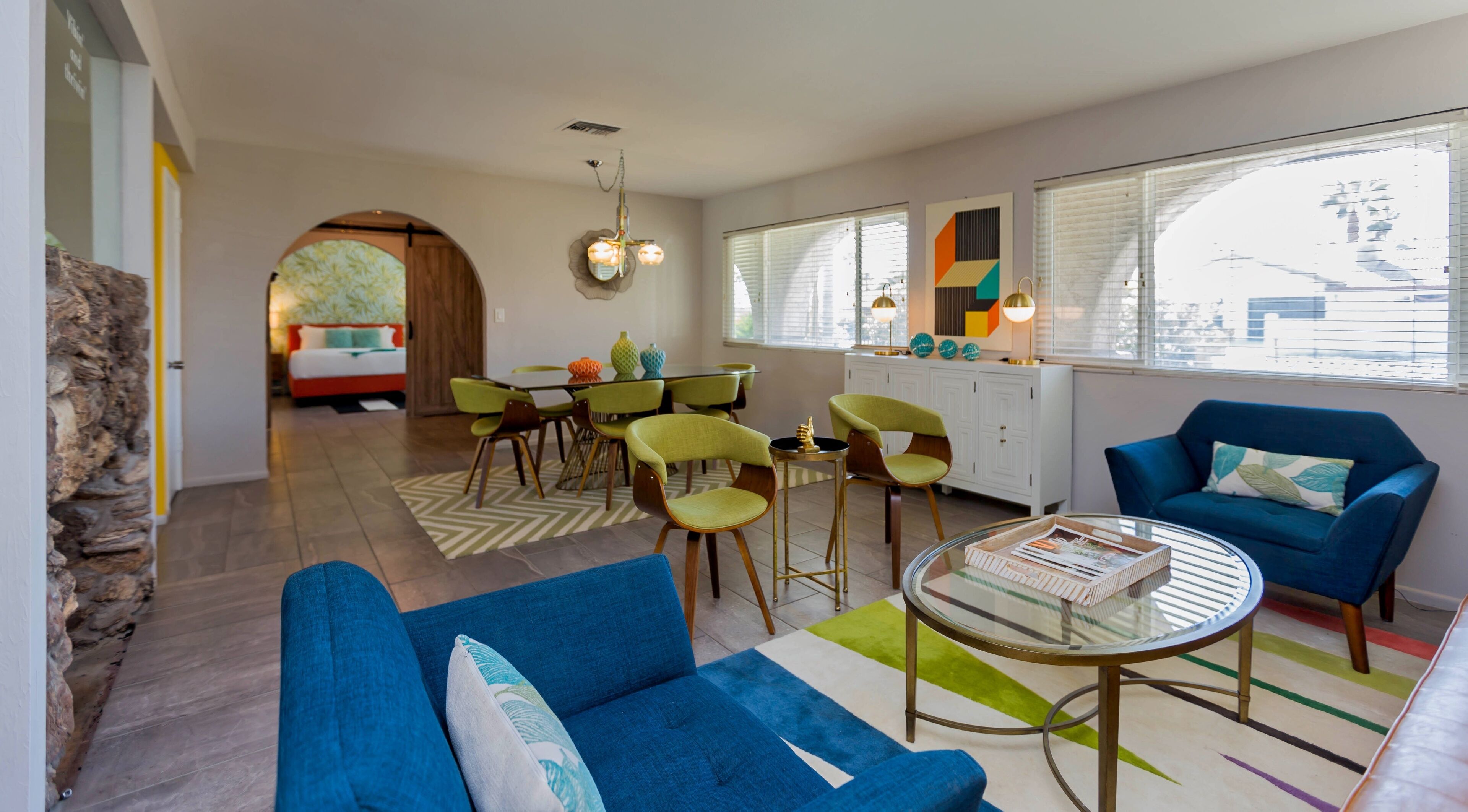 Een moderne woonkamer met een bank, stoelen, een eettafel en een keukenhoek.